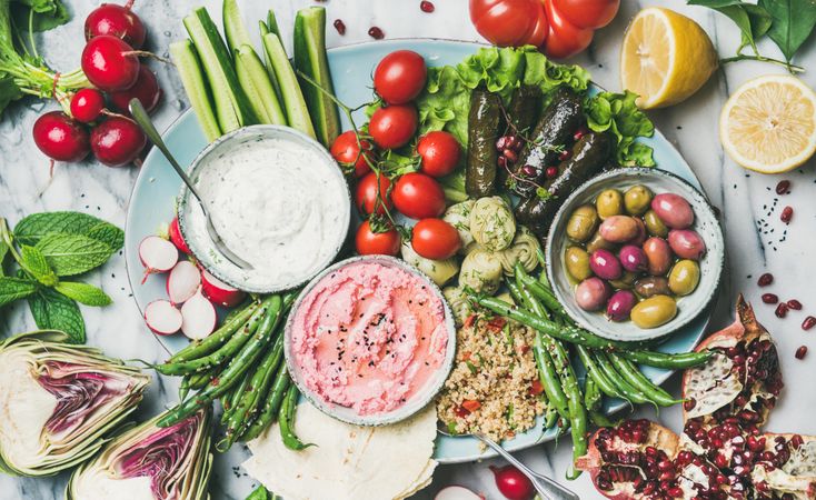 Fresh tray of snacks of fresh vegetables, olives, hummus, and dolmas