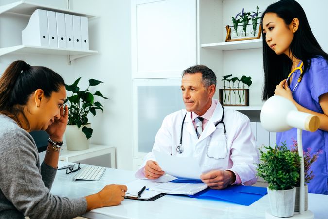 Concerned doctor discussing file with patient in office