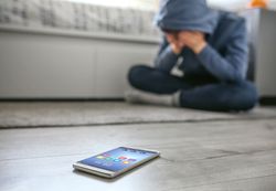 Teenager boy crying desperate for bullying with mobile lying on the floor in foreground