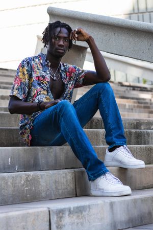 Stylish Black hipster man sitting on stairs in city