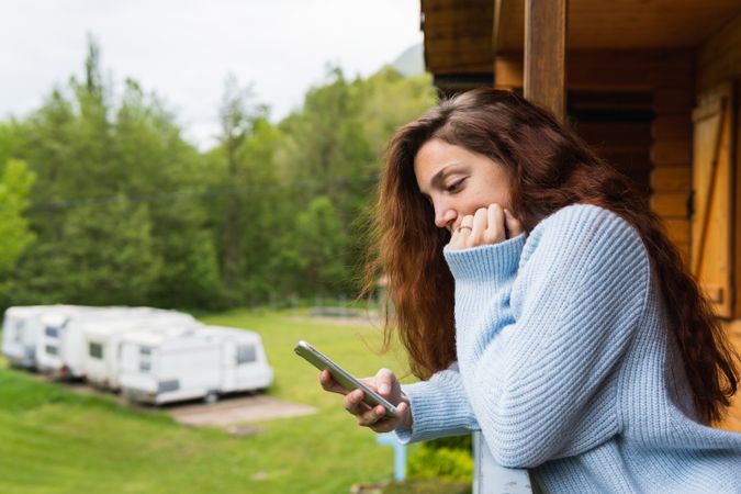 Pensive woman browsing on smartphone on terrace of house