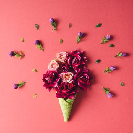 Roses and purple flowers and green waffle cone on dark coral background