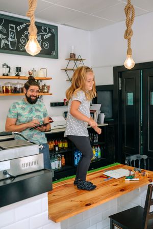 Father taking care of his daughter while working in a coffee shop.