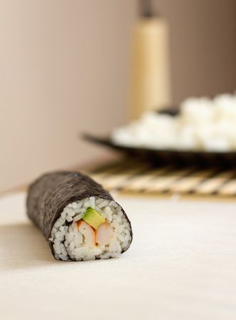Side view of sushi roll with rice, avocado and shrimps in nori