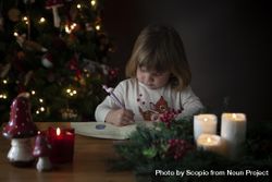 Girl writing letter for Santa beside Christmas tree 4mGMo0