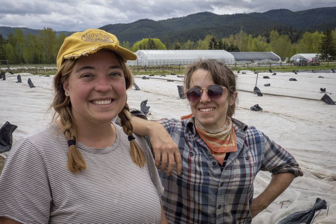 Two smiling women in front of field they planted