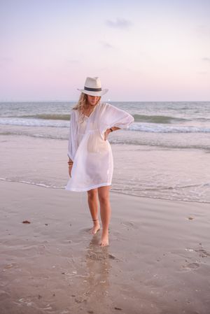 Charming woman in light white dress on wavy beach
