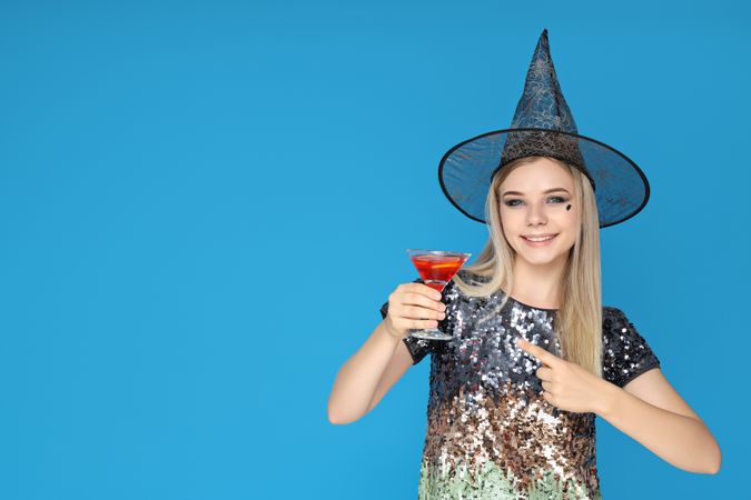 A woman at a party in the style of Halloween with a cocktail in her hands