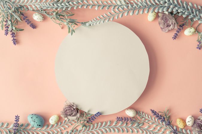 Creative layout made with spring flowers leaves and Easter eggs on pastel pink background