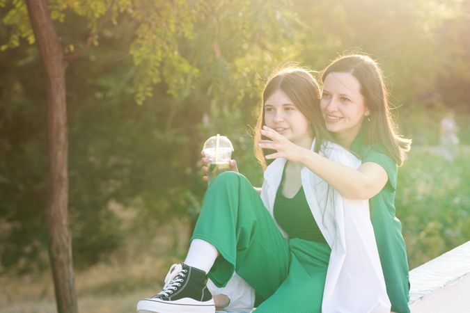 Mom and teenage daughter drink soft drinks on walk
