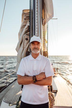 Portrait of older man with arms cross on sailboat at sunset