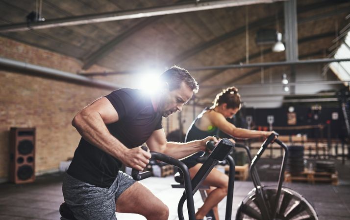 Muscular male exerting himself on cycle machine