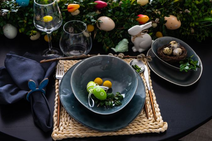Dark plates with decorative Easter eggs on spring themed table