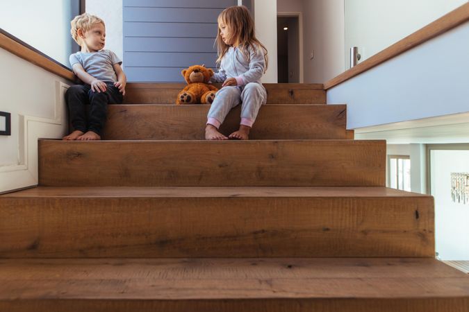 Conflict between little siblings for a toy while sitting on stairs at home