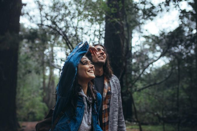 Happy woman shielding her face from the rain in a forest