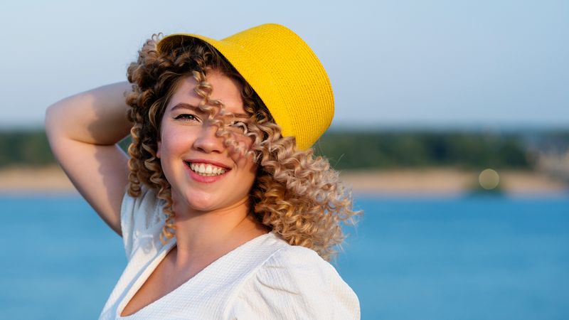 Portrait happy female in yellow hat in windy outdoors