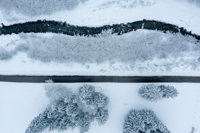 Road and mountain river in a winter snowy scenery, drone aerial view