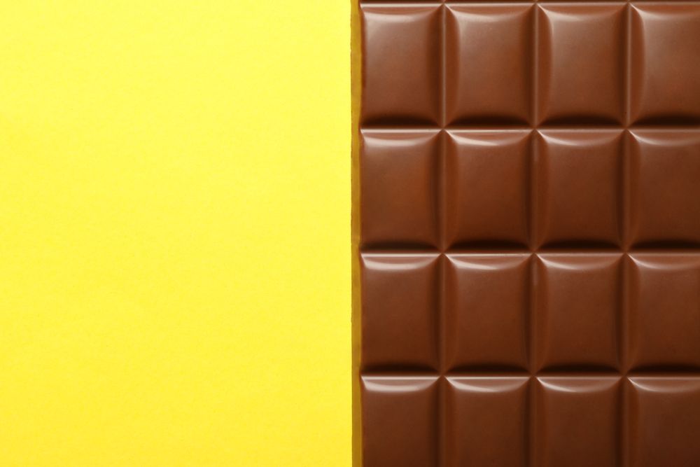 Tasty chocolate bar on yellow background. Sweet food
