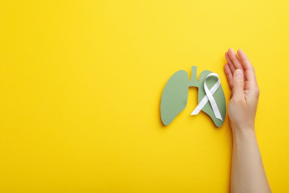 Lungs cut out of green paper with ribbon held by hand with copy space