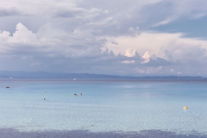 Seascape with white clouds and people swimming