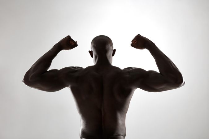 Rear view of male fitness model with masculine physique in silhouette