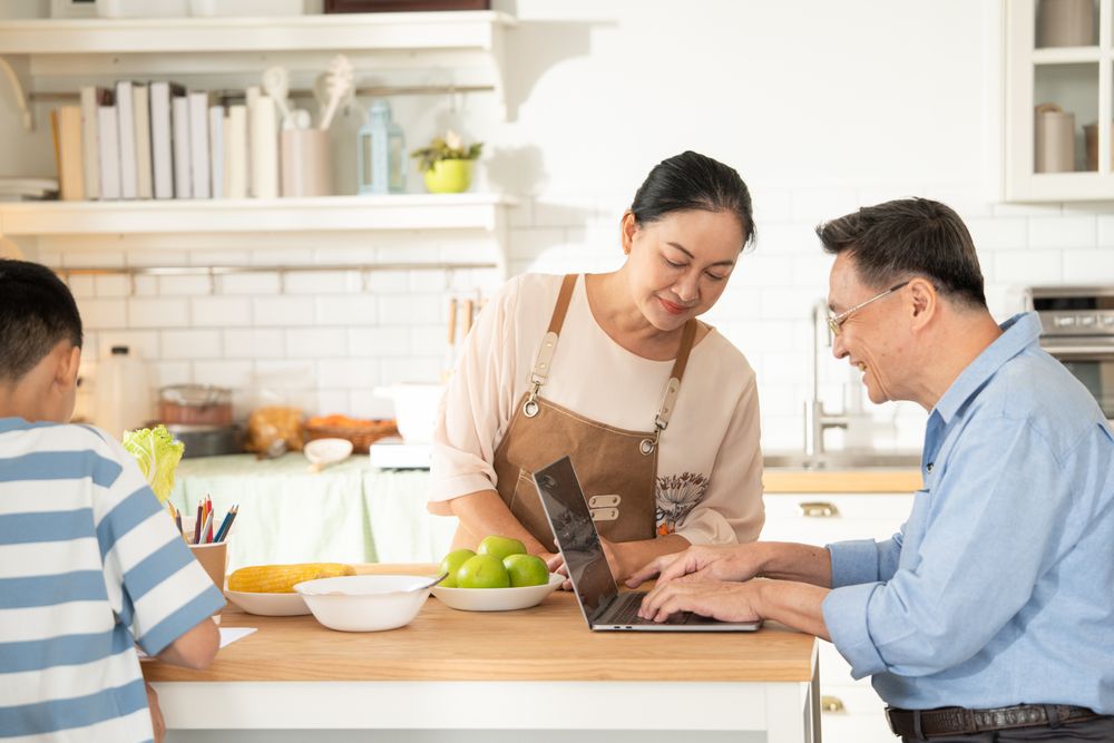 Asian grandmother watching and talking with grandson while doing homework