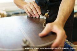 Cropped shot of male hands shaving back of guitar in luthier workshop 5pROjb