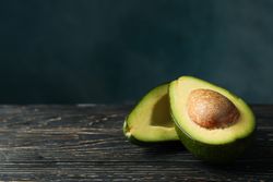 Ripe fresh avocado on wooden table, space for text