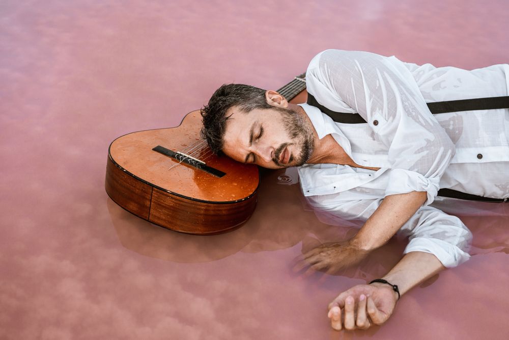 Man resting in water with guitar at seaside