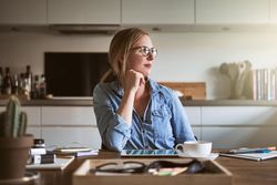 Woman gazing out of window from kitchen table