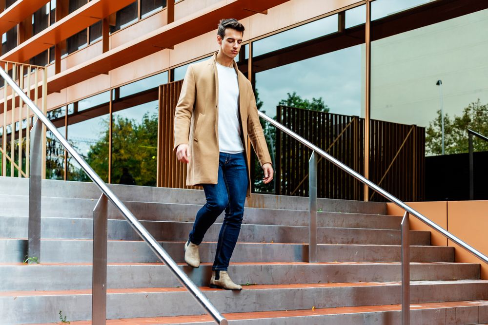 Man in fall coat walking down staircase outside