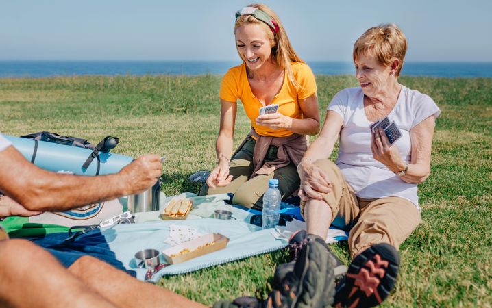 Smiling family playing card game during a picnic near the ocean