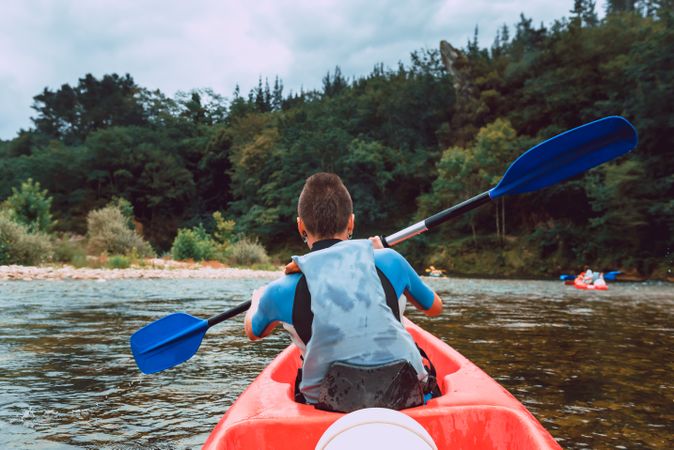 Female kayaking with paddle in raised hands