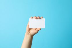 Female hand holding empty business card on blue background