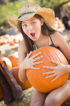 Girl Holding A Large Pumpkin at the Pumpkin Patch.