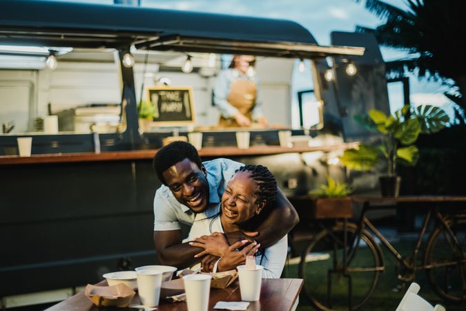 Happy Black couple hugging near food truck