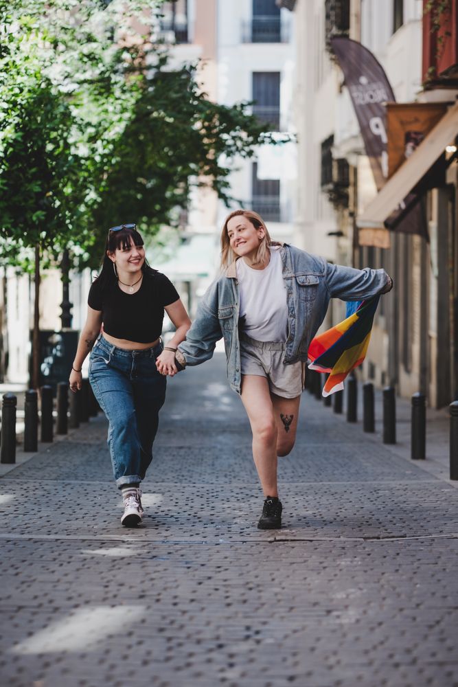 Lesbian couple with LGBT flag walking on street
