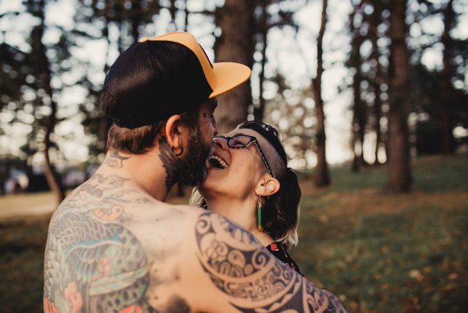Young guy in tattoos hugging woman in forest