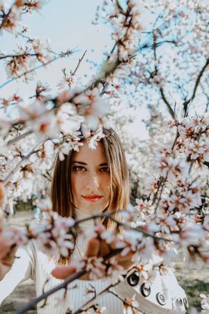 Young happy woman between trees in garden
