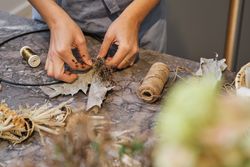 Crop woman in process of making floral wreath