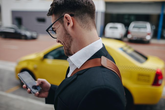Side view of a businessman walking on street looking at his mobile phone