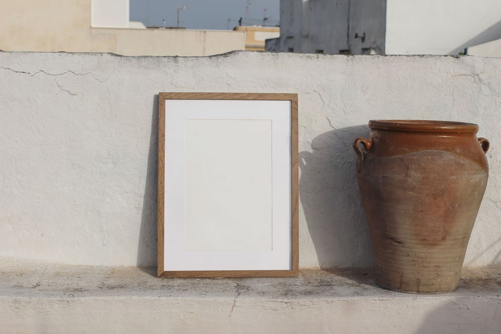 Blank vertical wooden frame picture mock up with vintage olive clay storage pot, vase