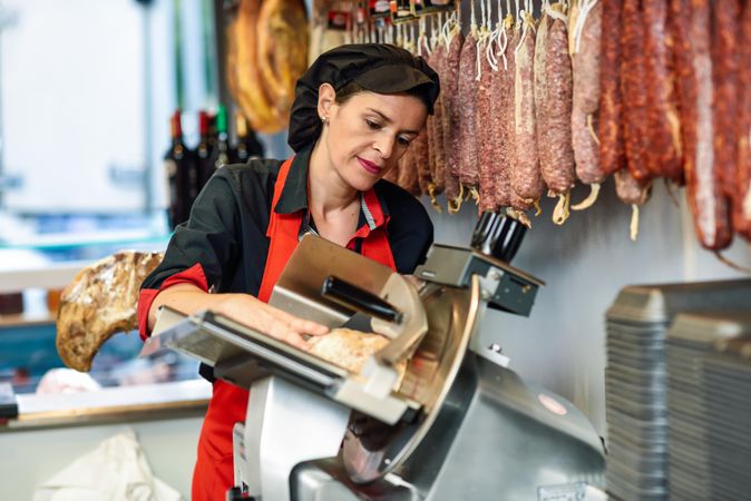 Woman in butcher shop slicing meat