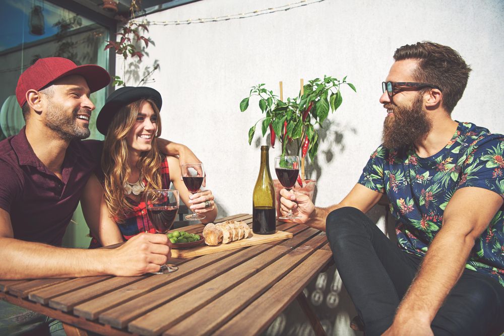 Bearded man with couple drinking wine in summer