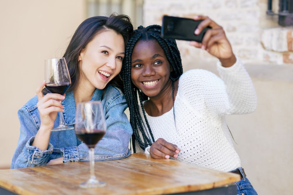 Female friends at a restaurant with red wine taking a self portrait