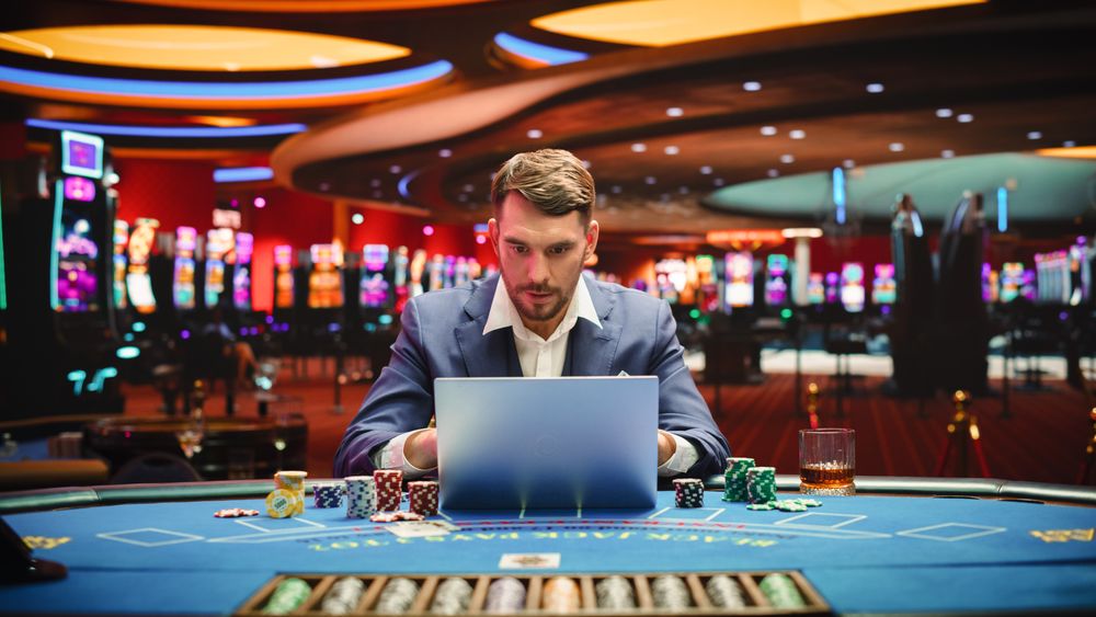 Portrait of a Happy Young Man in a Suit Using a Laptop Computer in Casino.
