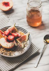 Flat-lay of yogurt bowl with fruit with honey and spoon