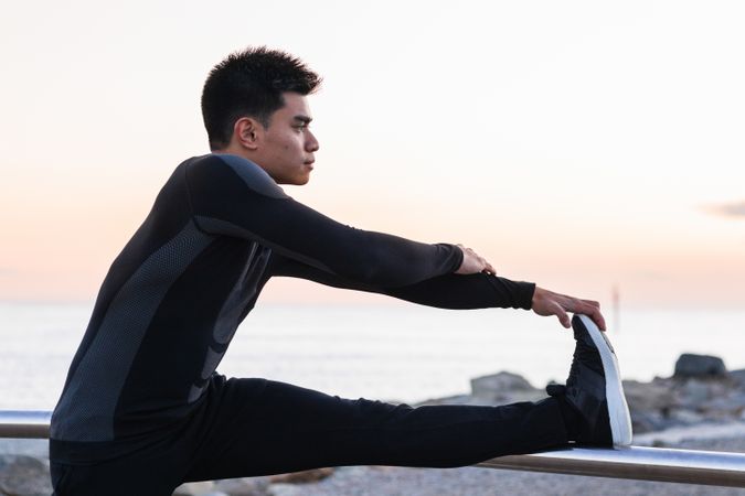 Asian man stretching legs during outdoor workout