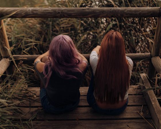 Women sitting on wooden pier in nature