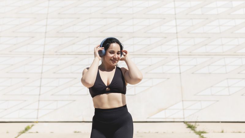 A young woman, dancing and moving, happy, while listening to music with headphones and disconnecting, to relax, after exercising